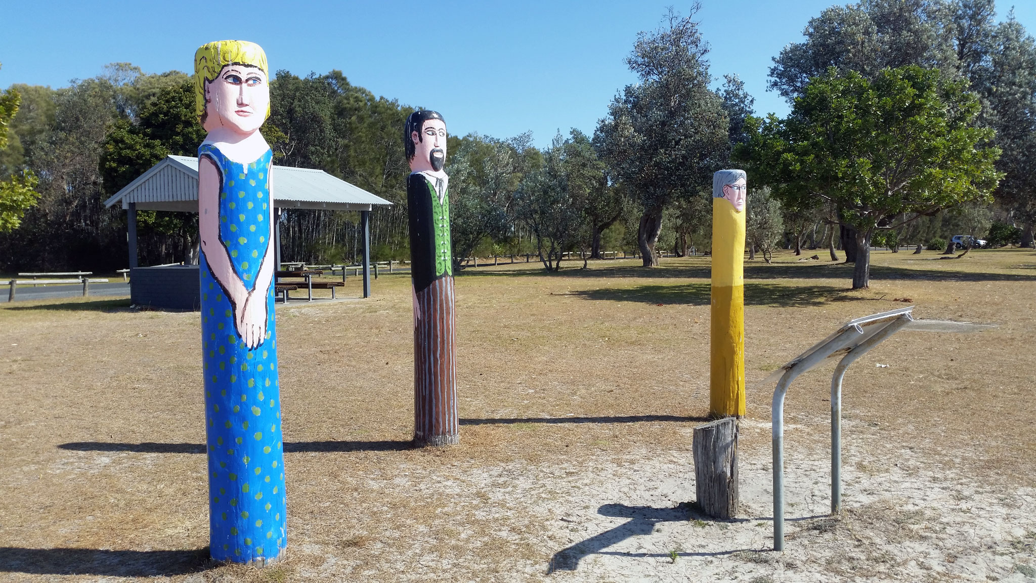Photo of 3 wooden totem poles built by the shed